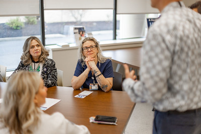 A group of people at a desk listening to a presentation.