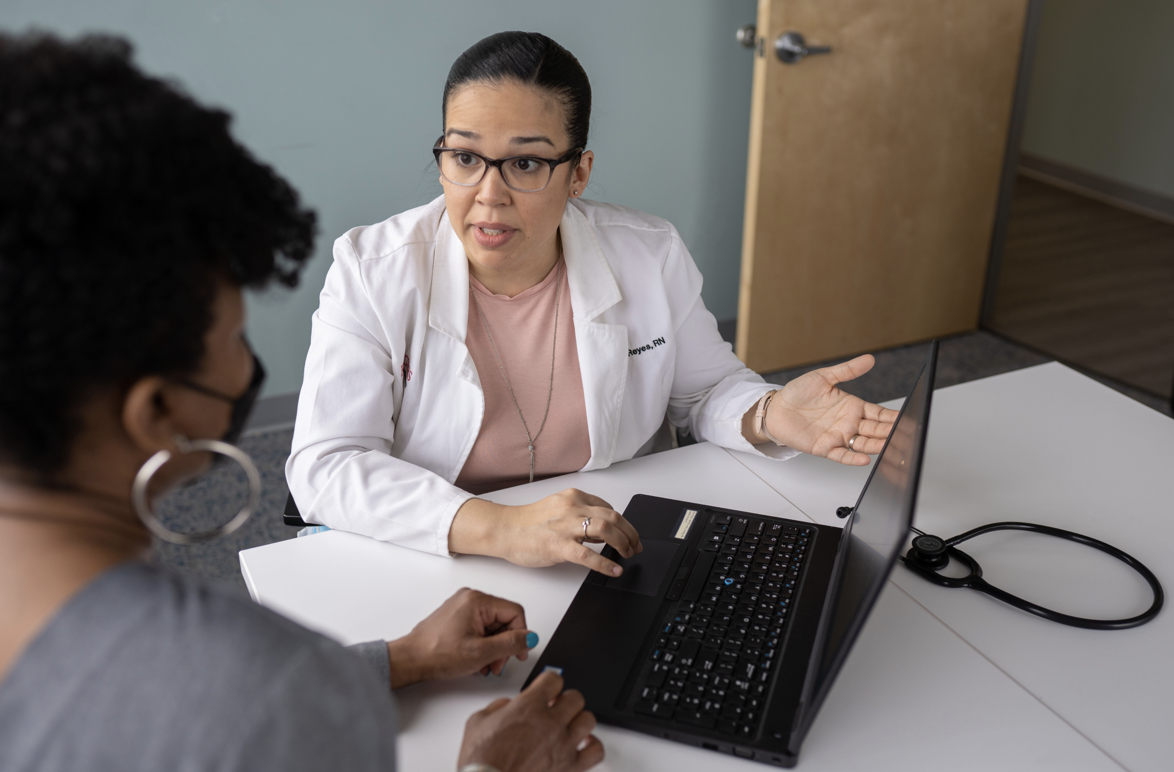 Stock image of a doctor treating a patient in front of a laptop